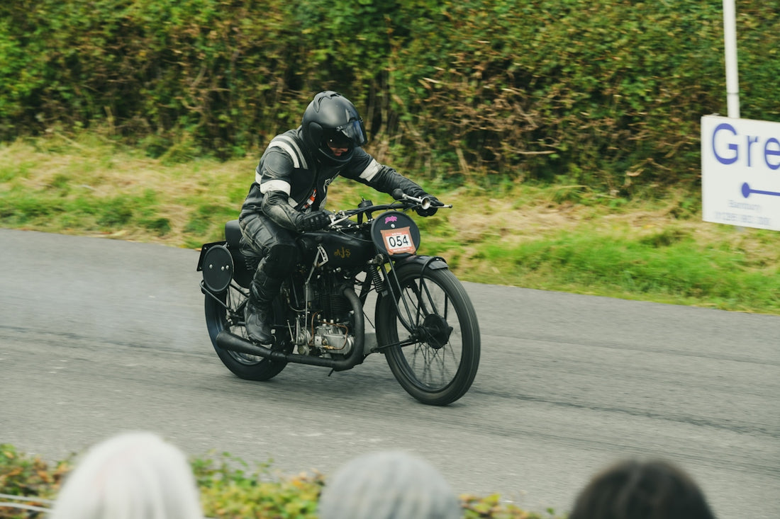 Rider in black racing vintage motorcycle on road